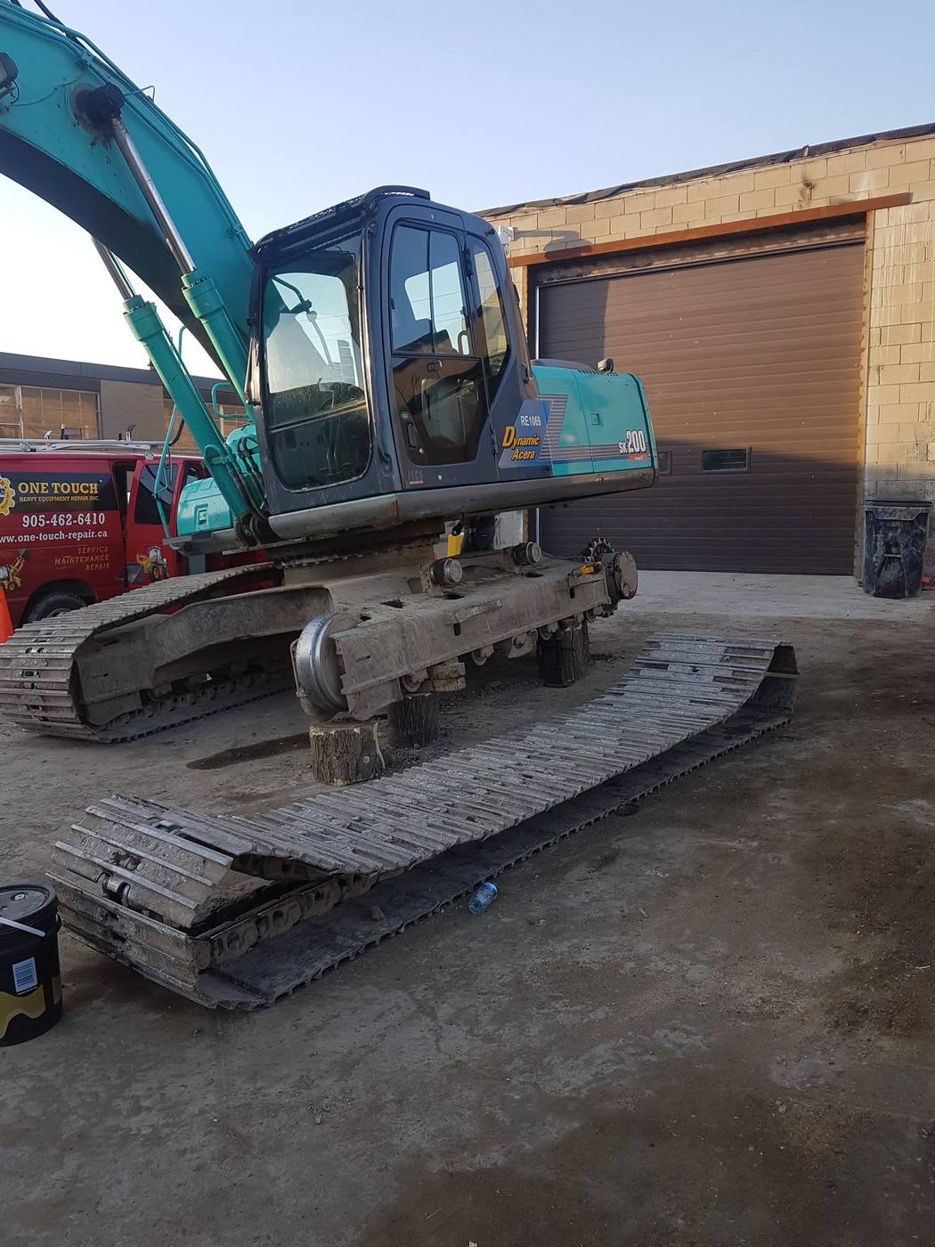 Kobelco SK200 excavator on cribbing with track removed for undercarriage service, One Touch service truck on site